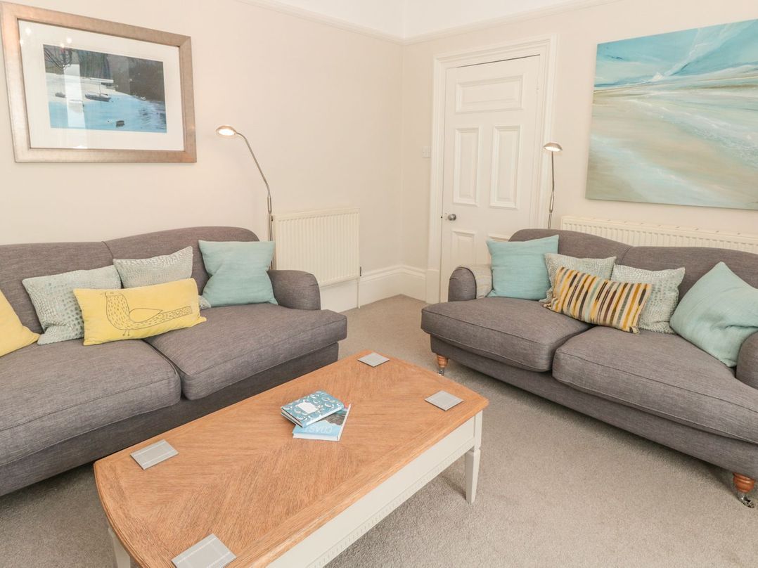 A living room with two grey sofas and a wooden coffee table with books at Leylands in Salcombe