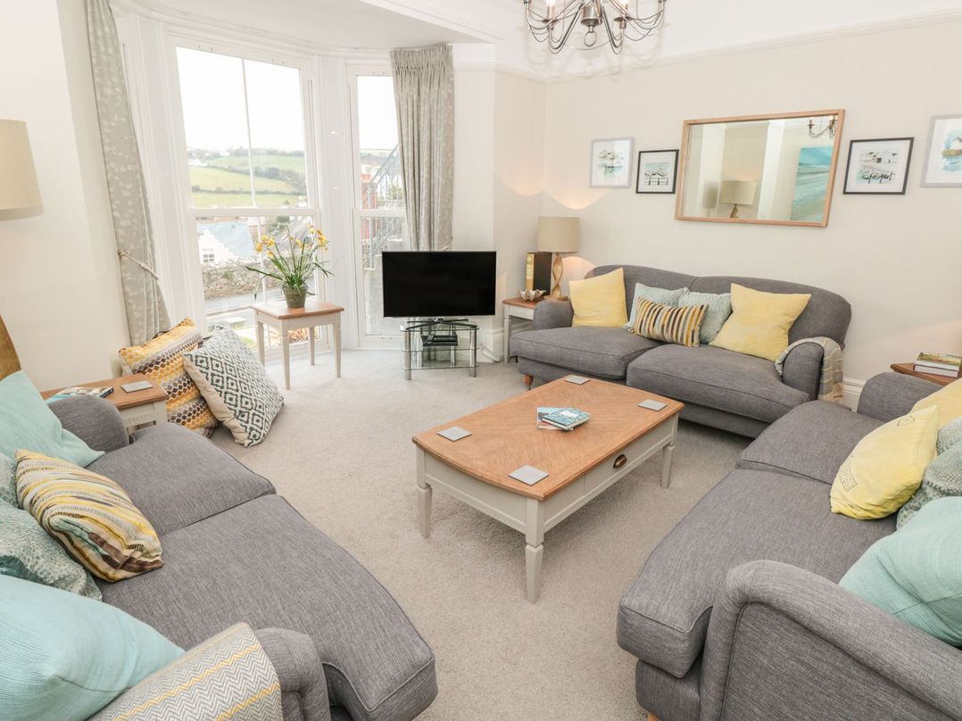A living room with three gray sofas cushions a wooden coffee table and a television at Leylands in Salcombe