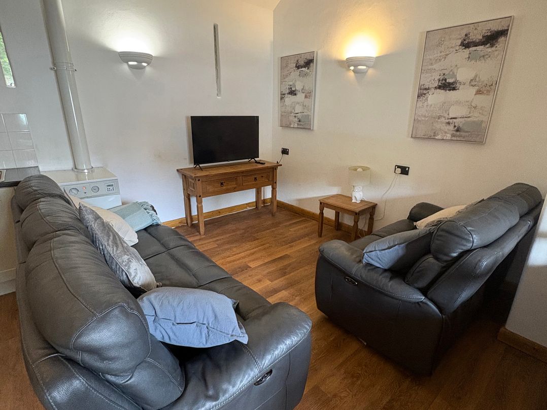A living room with a sofa and TV at Woodside Cottage in Kerry