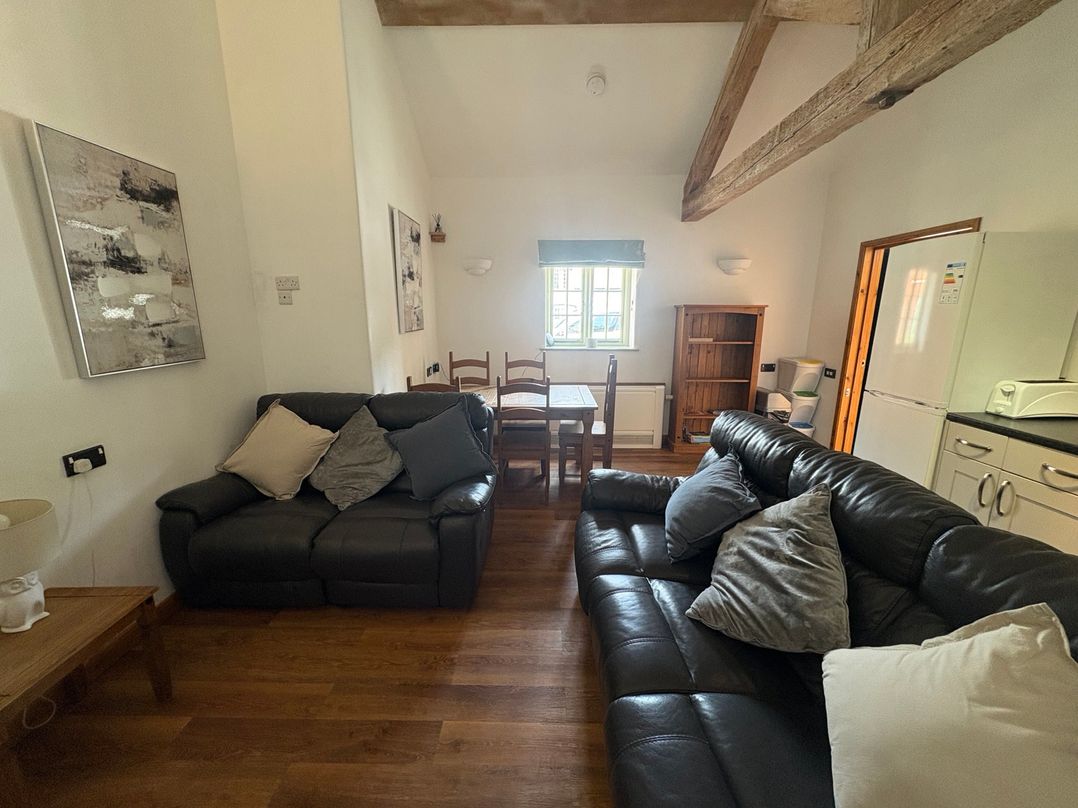 A living room with a sofa and dining table at Woodside Cottage in Kerry