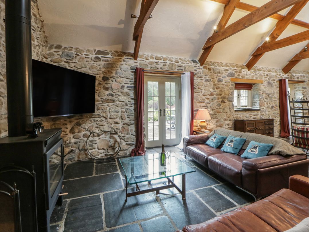A living room with a television and a leather sofa at St Dogwells Barn near Wolfscastle