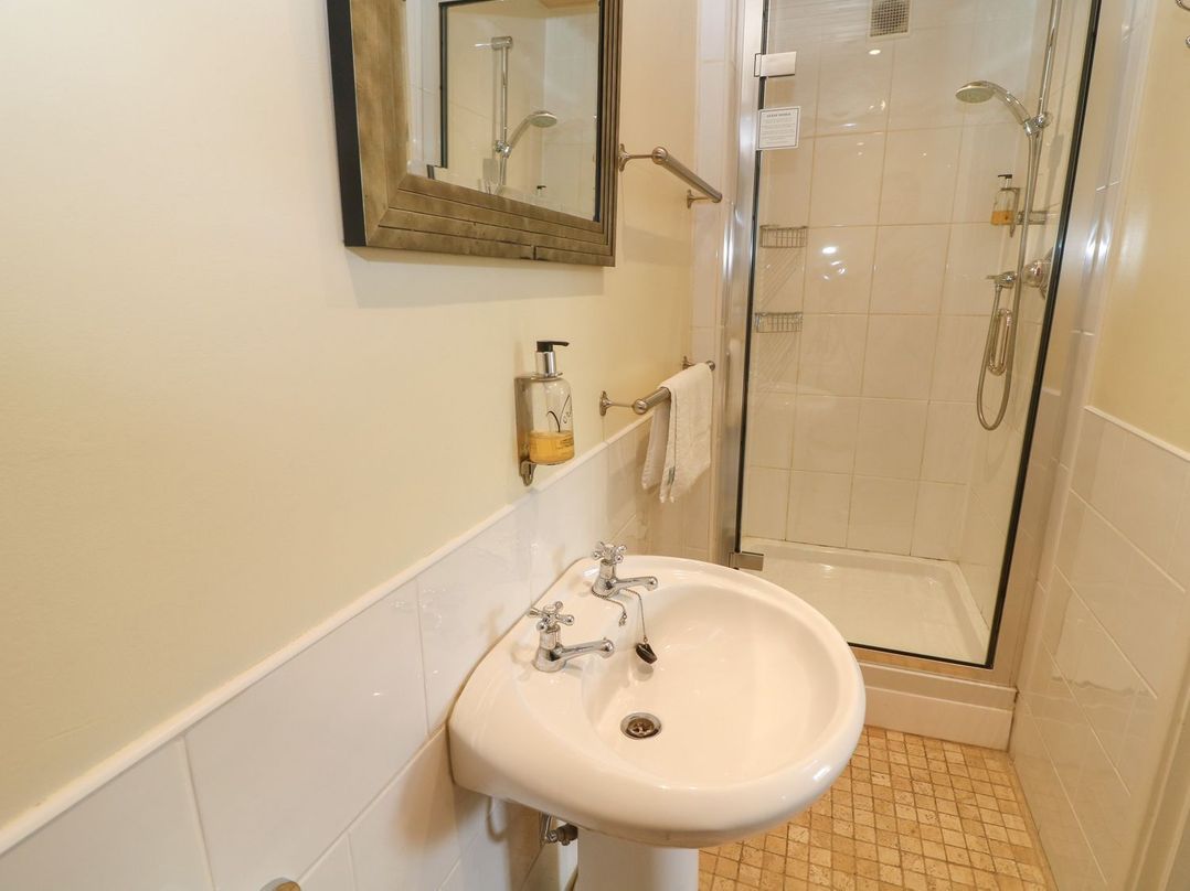 A bathroom with a pedestal sink a mirror a soap dispenser a towel rack and a glass-enclosed shower at Kearton Shunner Fell Thwaite near Muker