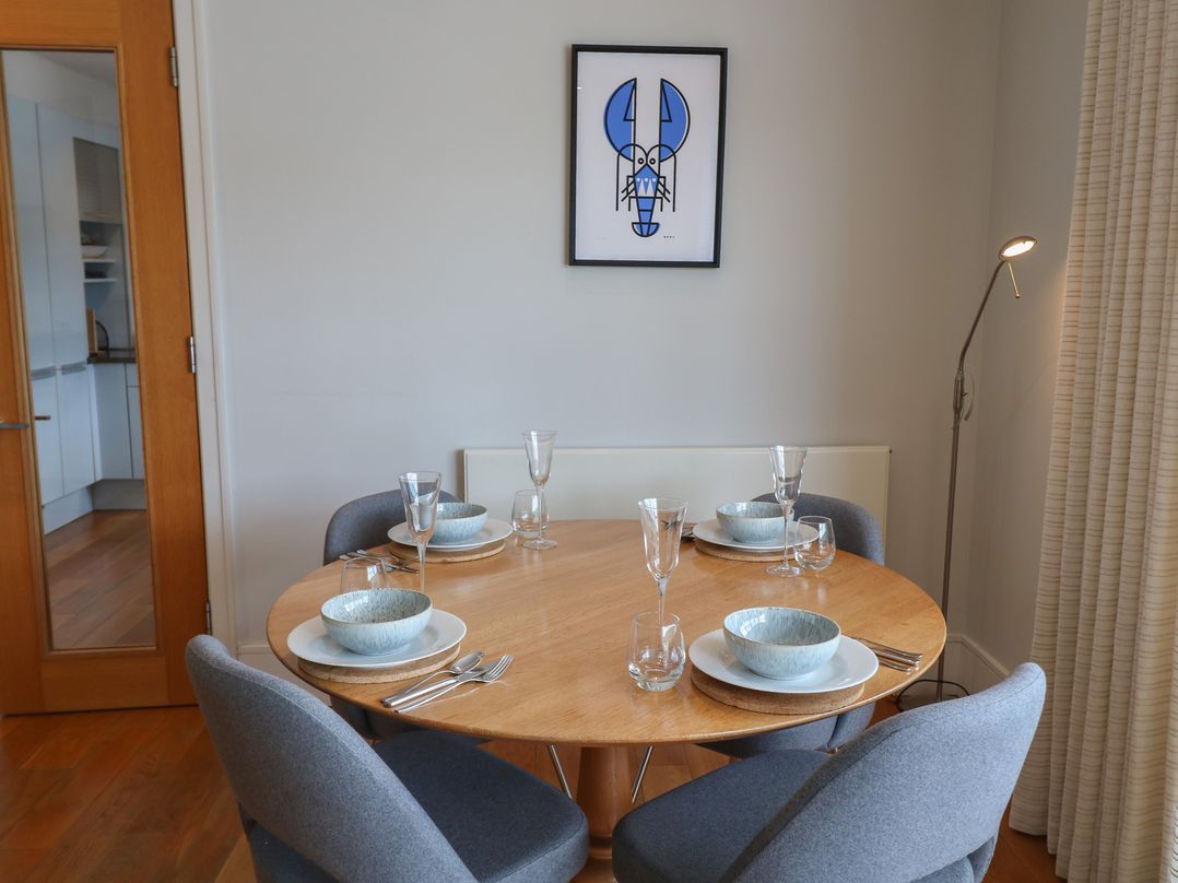 A dining room with a round table set for meals at 22 Dart Marina in Dartmouth