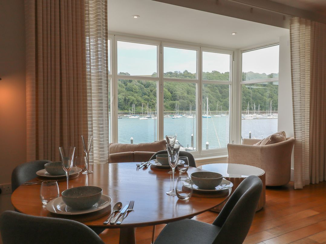 A dining room with a table set for meals and a view of the marina at 22 Dart Marina Dartmouth