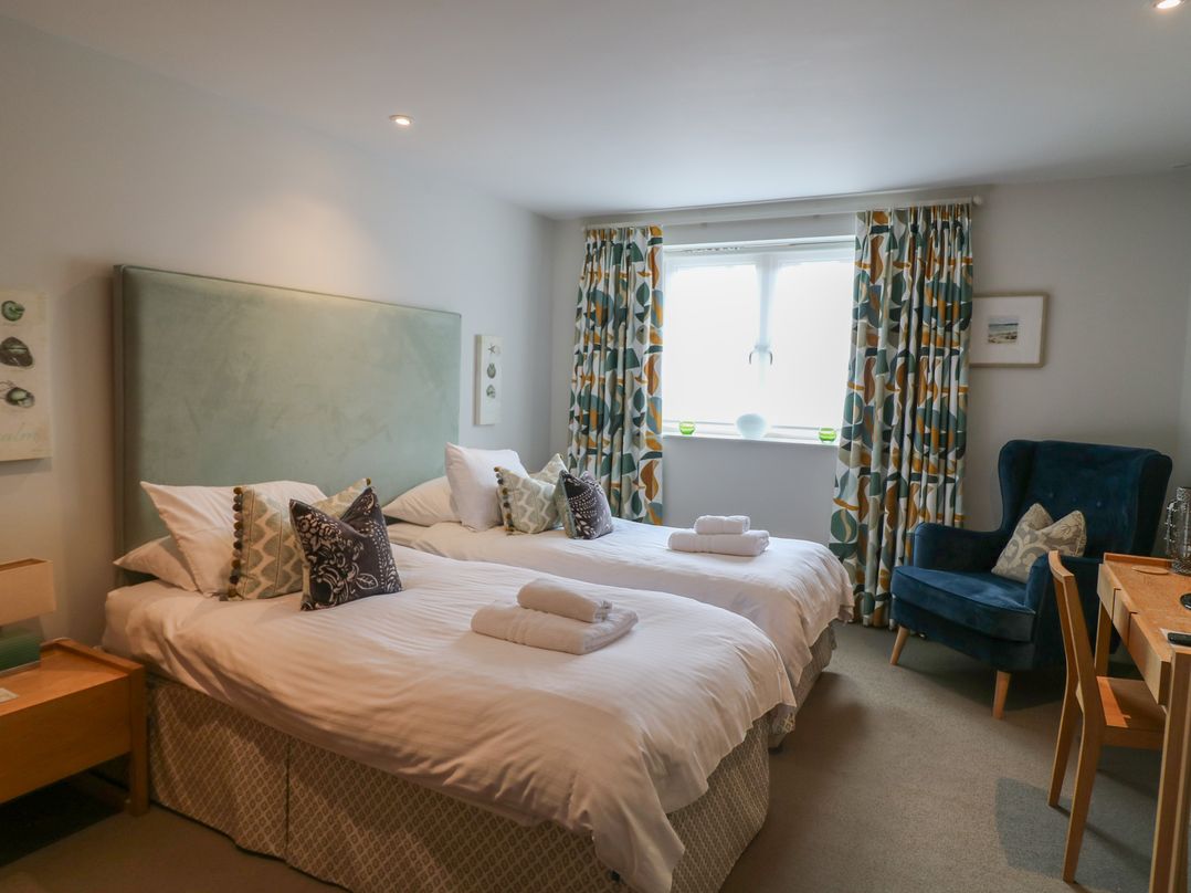A bedroom with two beds and an armchair at 22 Dart Marina Dartmouth