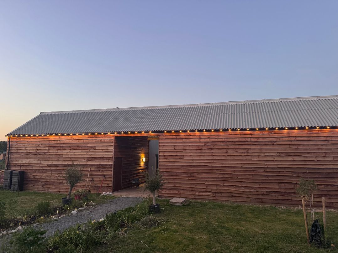 An exterior view of a wooden building with lights at Number 3 The Barn House in Woodham
