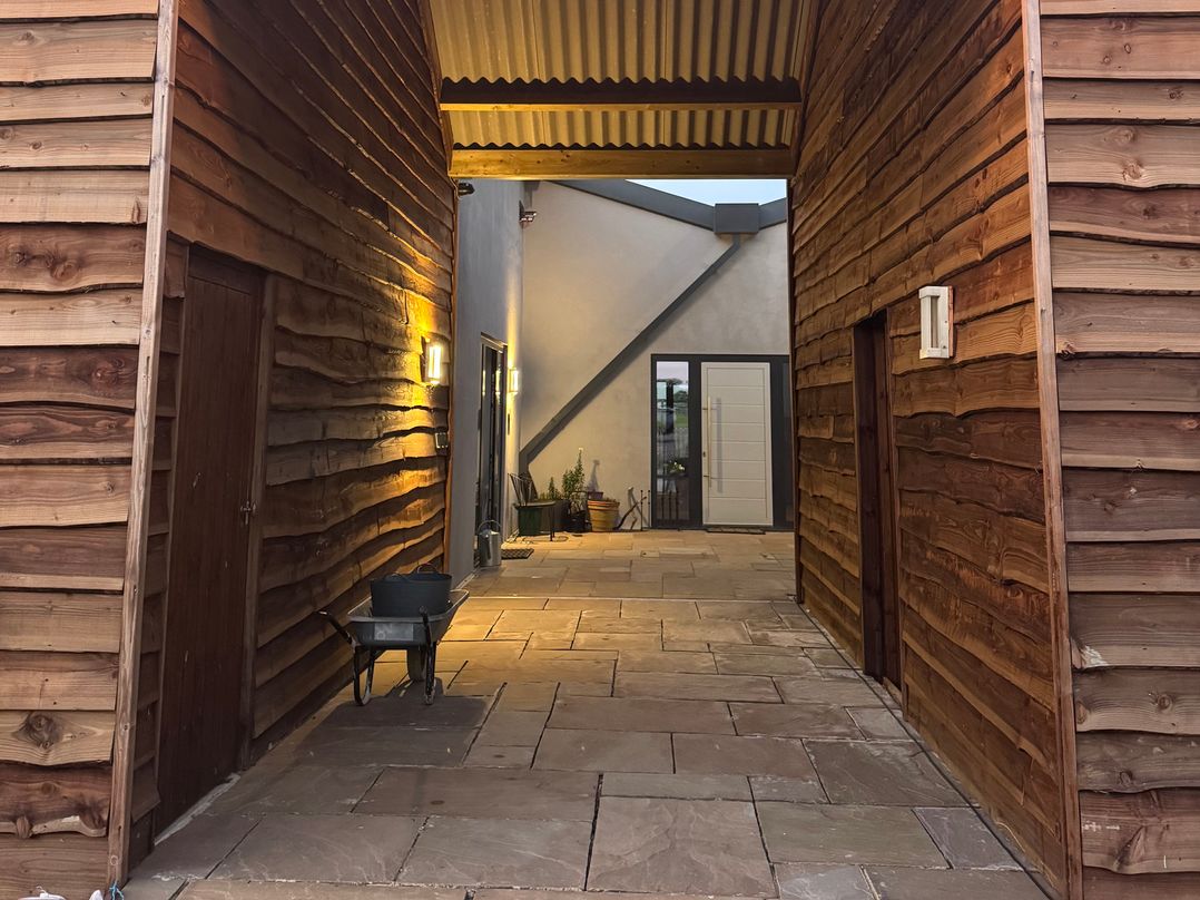 An outdoor area with a paved walkway and wooden walls at Number 3 The Barn House Woodham