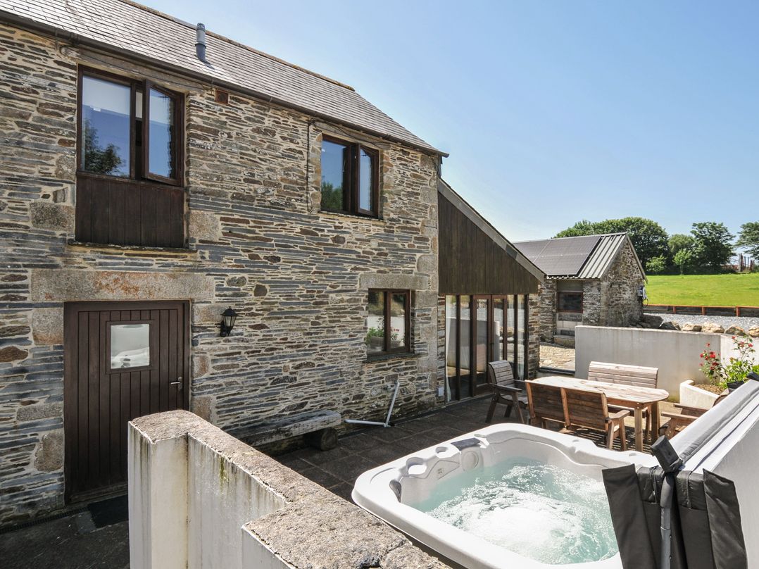 An outdoor area with a hot tub and seating at The Dairy Barn in Camelford