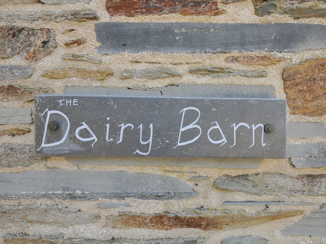 A sign for The Dairy Barn attached to a stone wall in Camelford