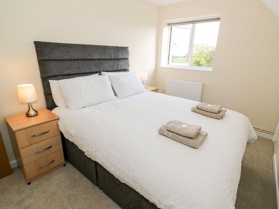 A bedroom with a double bed, bedside tables with lamps, and a window at Walnut Cottage in Welford-On-Avon