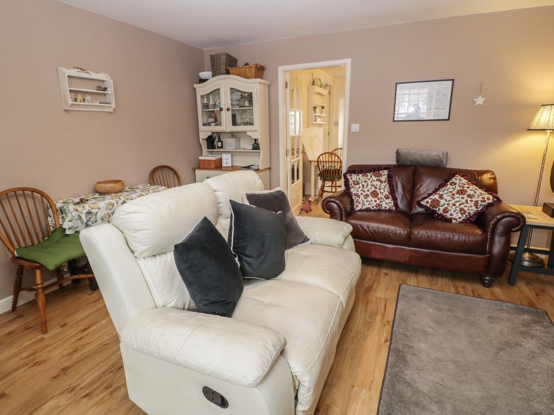 A living room with a leather sofa and dining table at Rose Cottage in Hartington