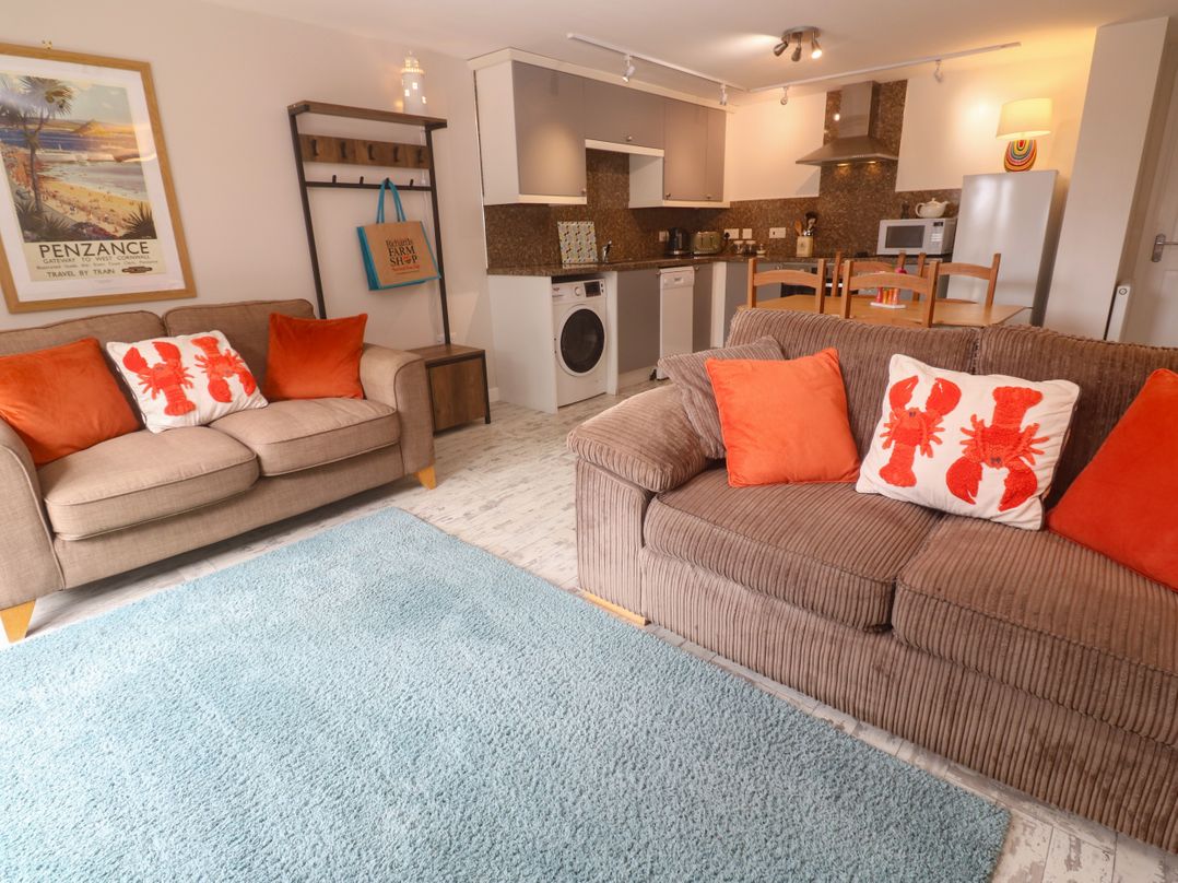 A living room with a sofa and kitchen area at The Packing House in Rosudgeon
