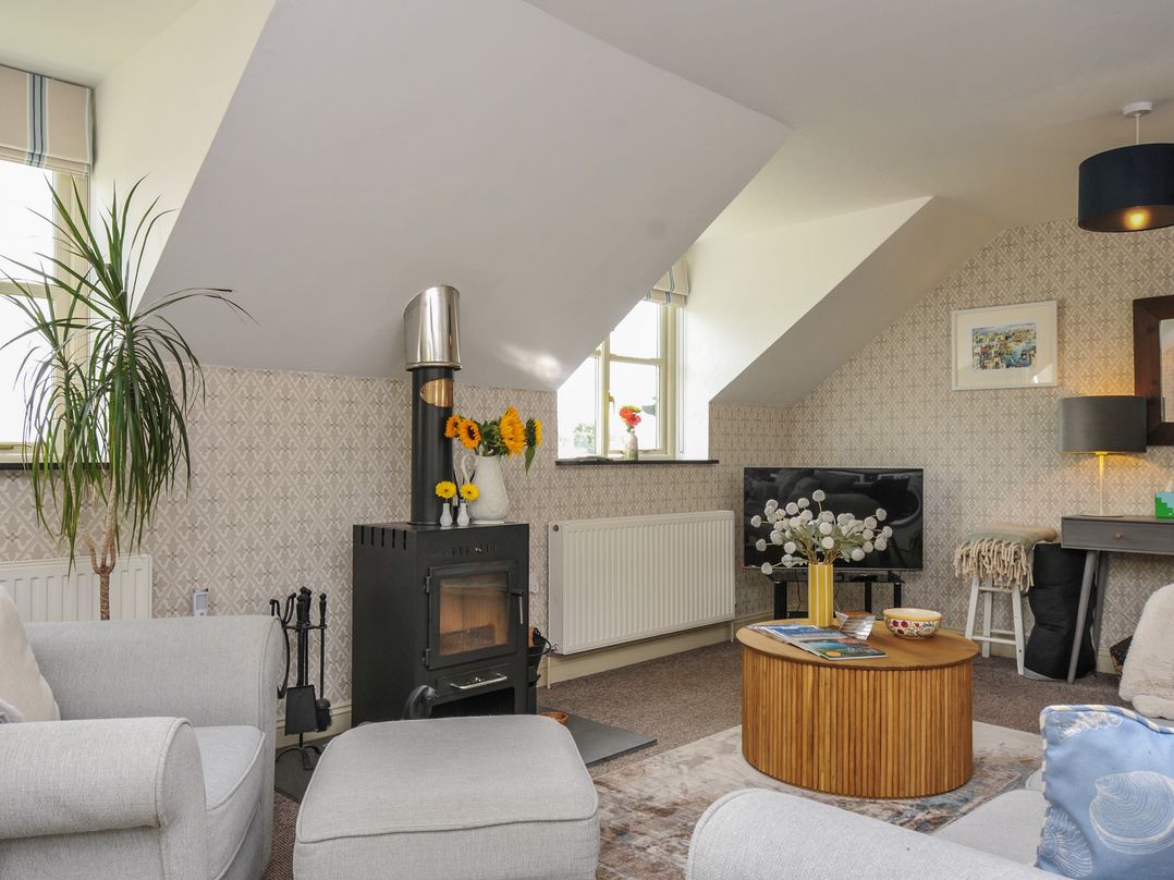 A living room with a faux fireplace and sofa at The Hayloft in Lostwithiel