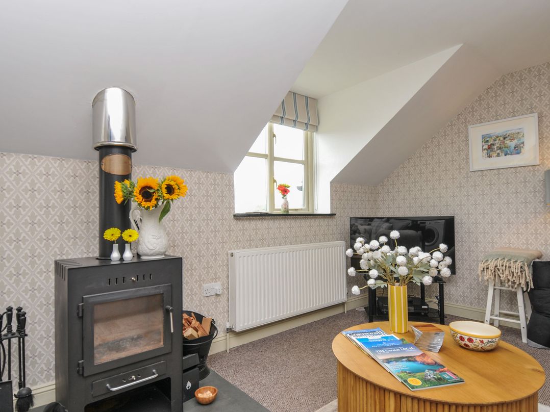 A living room with a wood stove and a television at The Hayloft in Lostwithiel