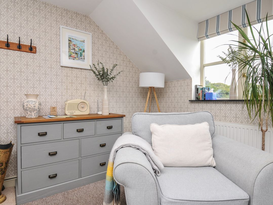A living room with a gray armchair and side table at The Hayloft in Lostwithiel