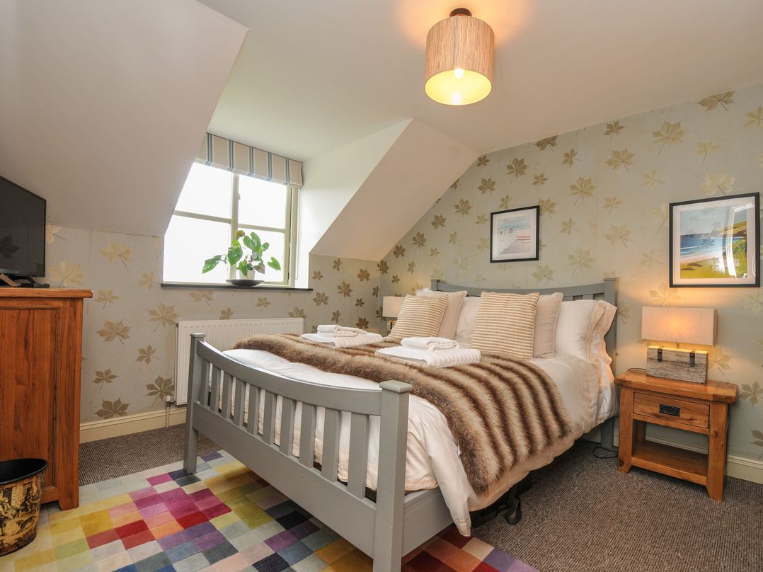 A bedroom with a bed, bedside table, and a television at The Hayloft in Lostwithiel