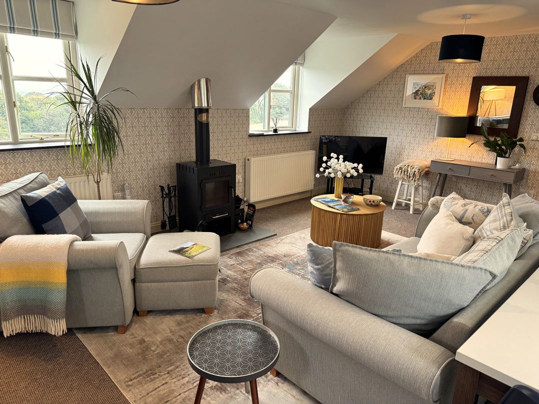 A living room with seating and a stove at The Hayloft in Lostwithiel