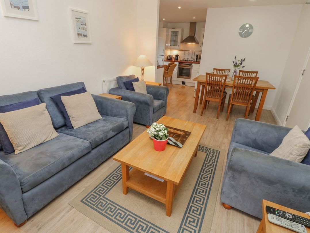 A living room with blue sofas and a wooden coffee table next to a dining table and kitchen at Pierpont D1 Norton near Yarmouth