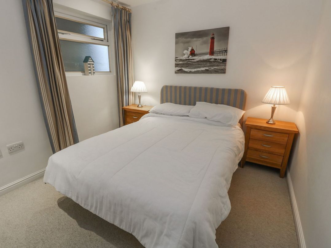 A bedroom with a bed white bedding two bedside tables with lamps and a window with curtains at Pierpont D1 Norton near Yarmouth