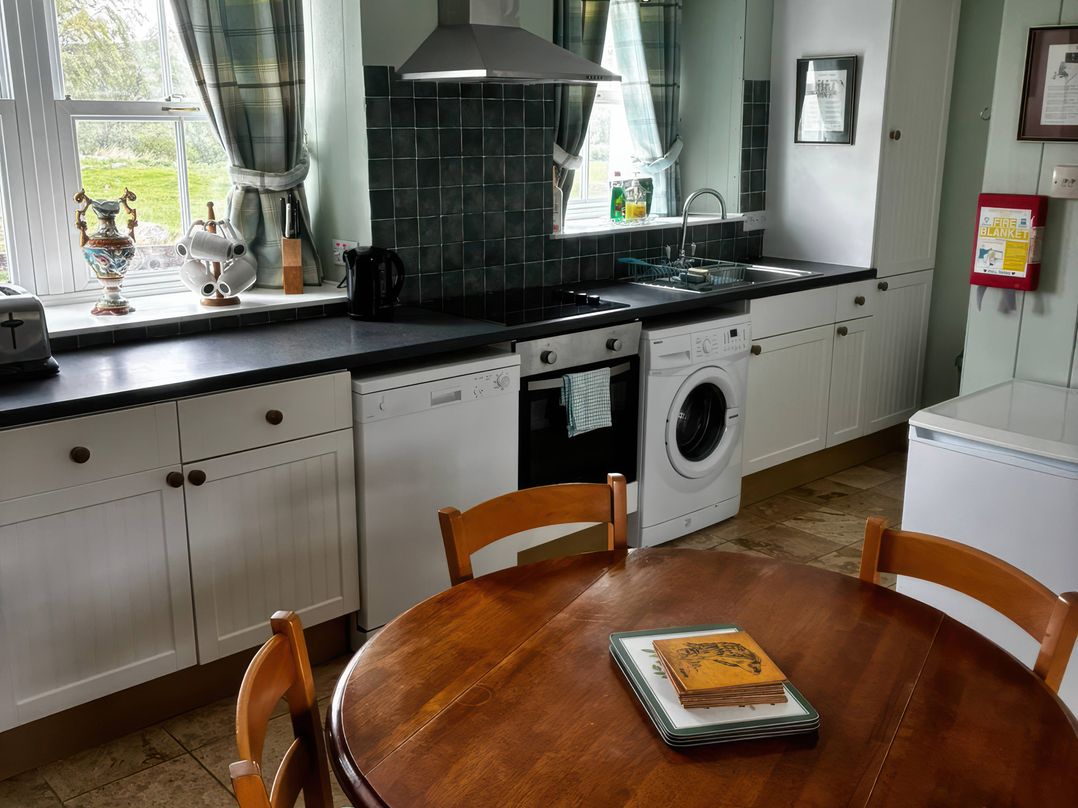 A kitchen with a table and appliances at Strathnoon in Clune near Carrbridge