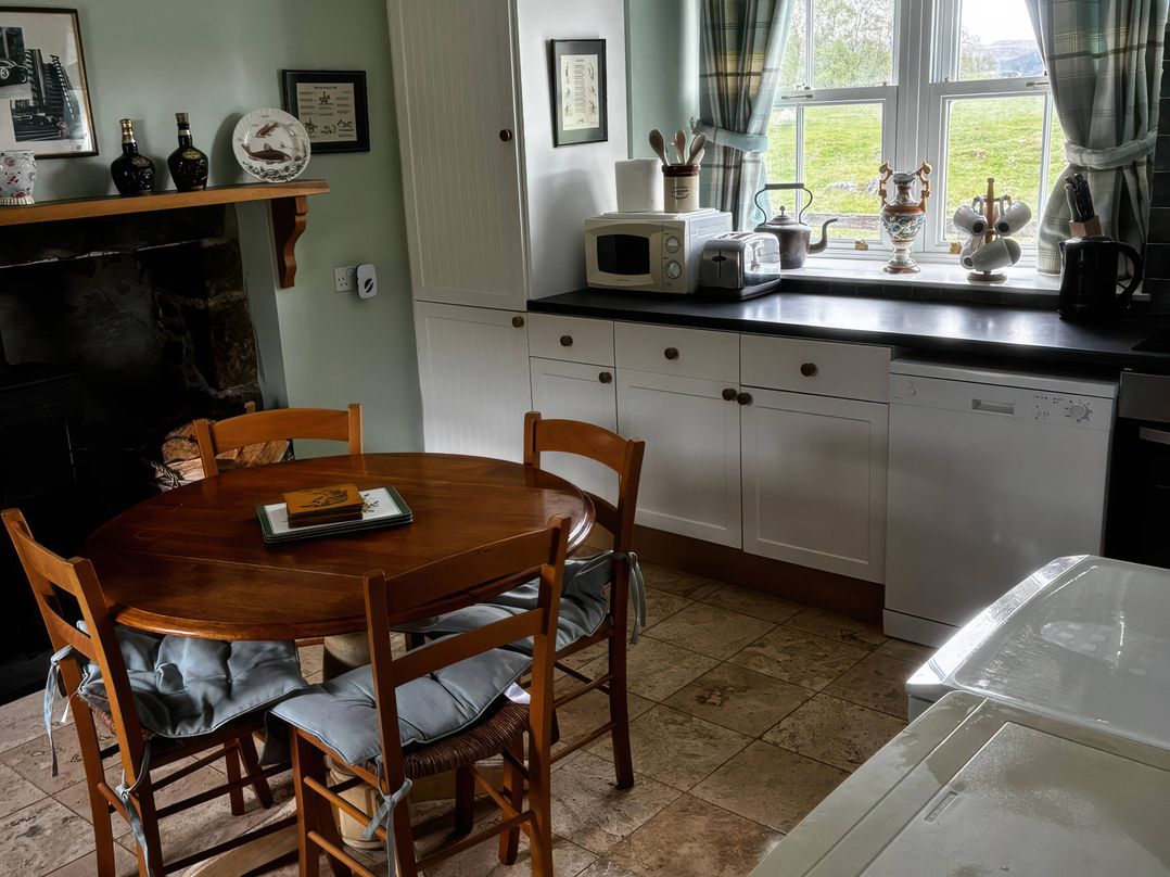 A kitchen with a round table and chairs at Strathnoon in Clune near Carrbridge
