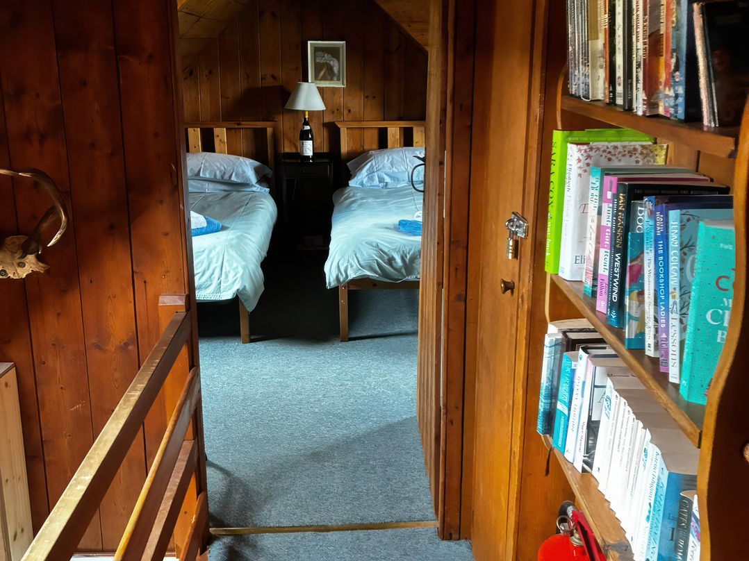 A bedroom with two beds and a bookshelf at Strathnoon in Clune near Carrbridge