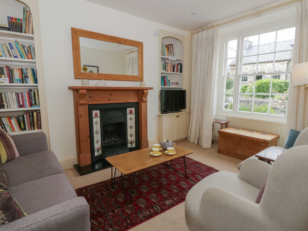 A living room with a fireplace and bookshelf at Ty Clyd in Newport, Pembrokeshire