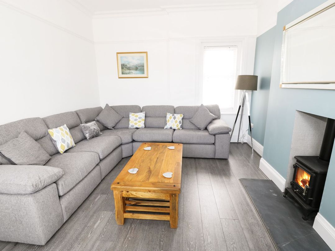 A living room with a grey sectional sofa wooden coffee table floor lamp and a fireplace at 51 Trinity Avenue in Llandudno