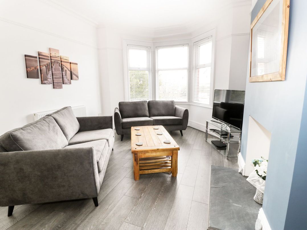 A living room with two gray sofas wooden coffee table and a flat screen tv on stand at 51 Trinity Avenue in Llandudno