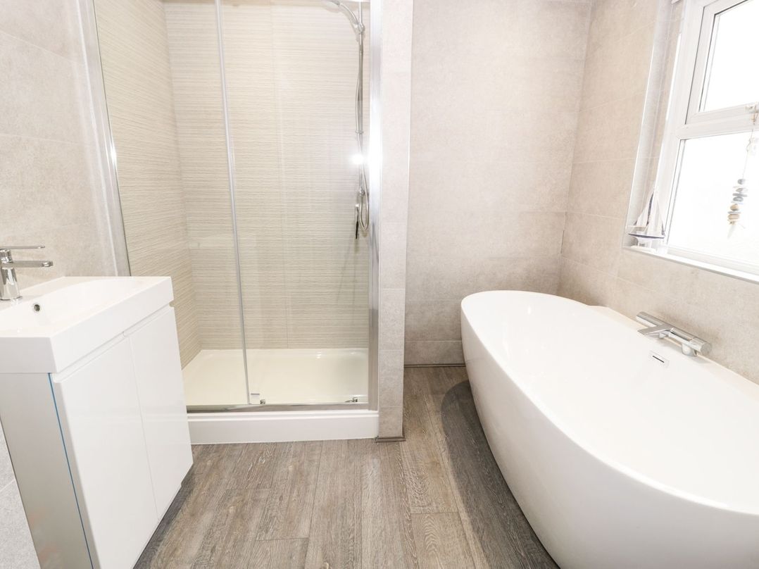 A bathroom with a sink cabinet shower enclosure and freestanding bathtub at 51 Trinity Avenue in Llandudno