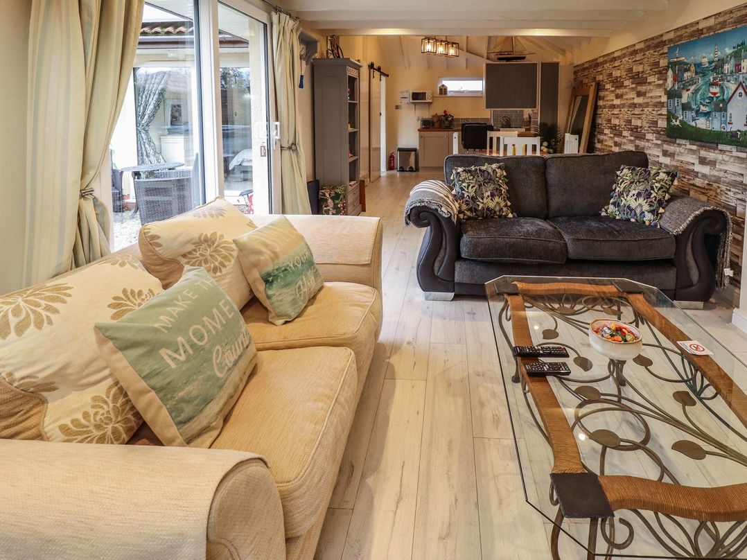 A living room with two sofas a glass coffee table and a kitchen area in the background at Sunnyside in Goxhill near Barrow-Upon-Humber
