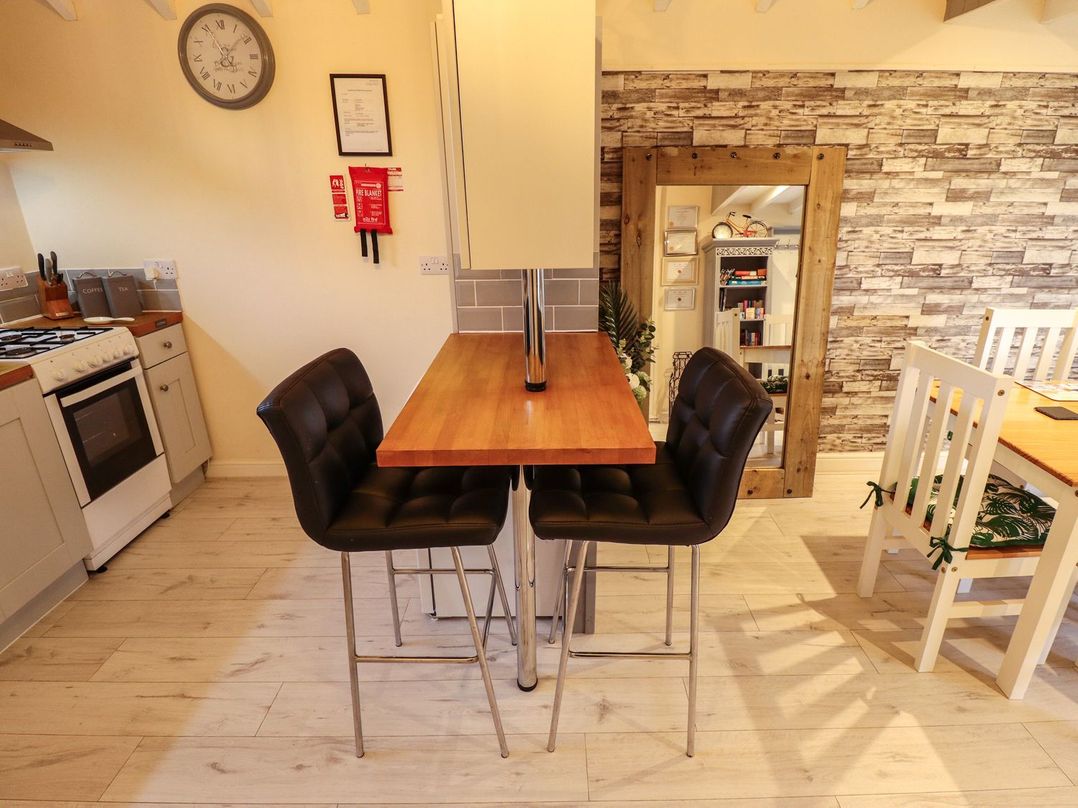 A kitchen area with a stove and countertop and two black bar stools next to a wooden table at Sunnyside in Goxhill near Barrow-Upon-Humber