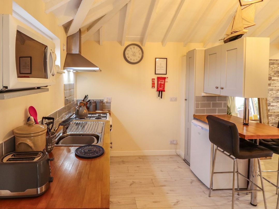 A kitchen with a wooden countertop microwave toaster sink stove and high chairs at Sunnyside in Goxhill near Barrow-Upon-Humber