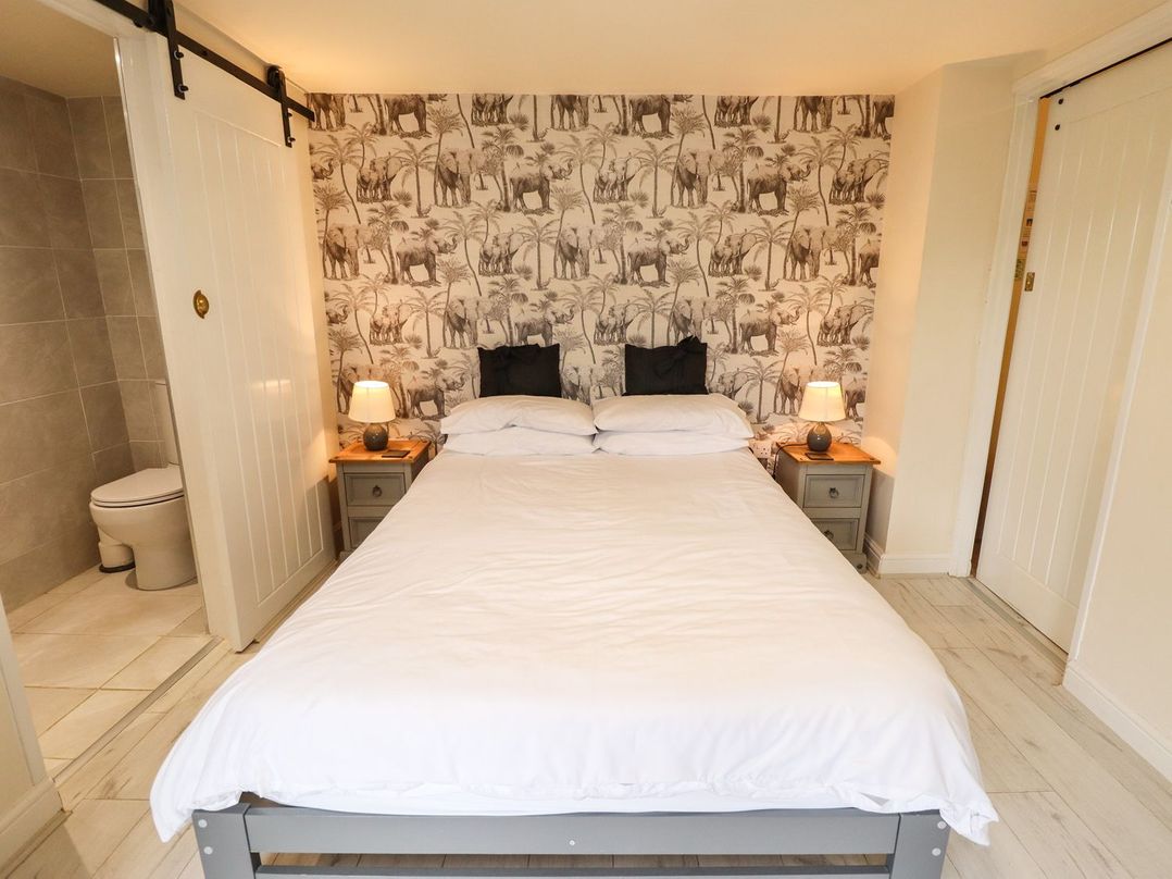 A bedroom with a double bed between two bedside tables with lamps and elephant wallpaper at Sunnyside in Goxhill near Barrow-Upon-Humber