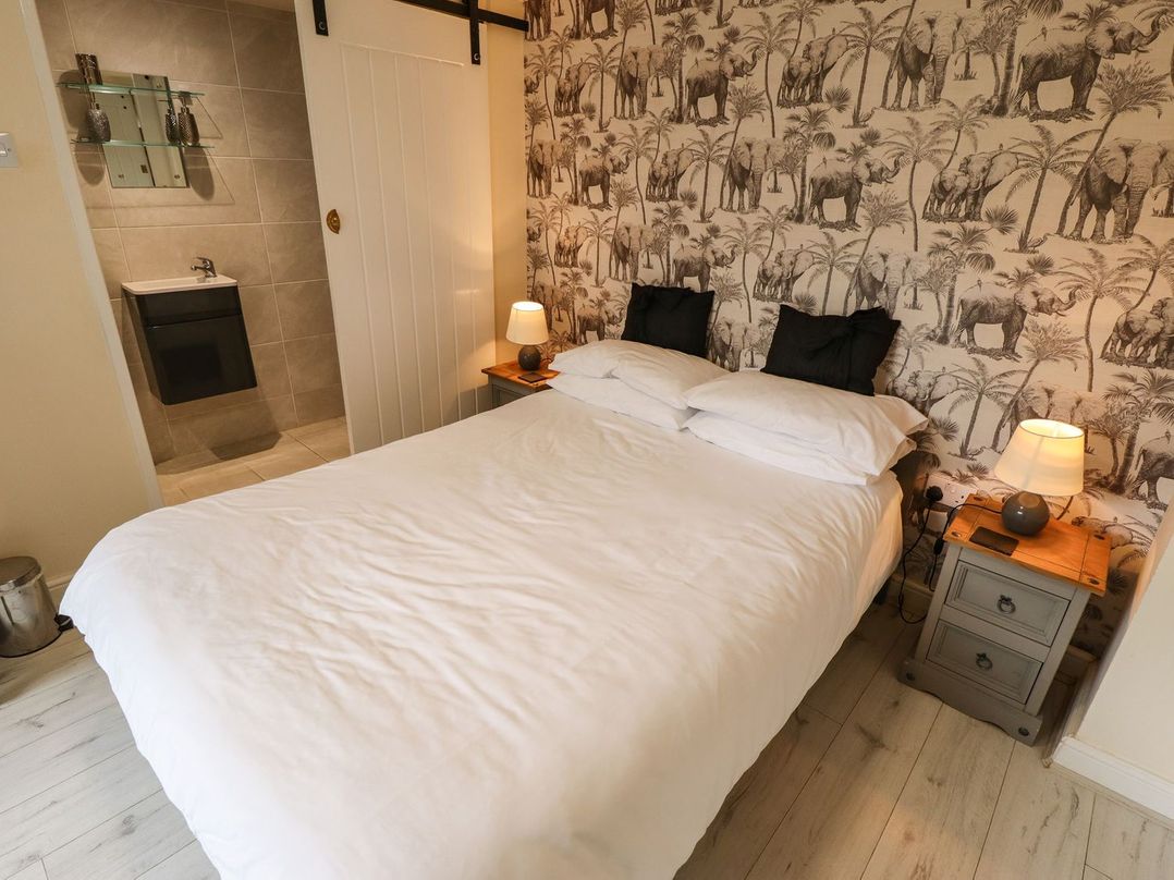 A bedroom with a double bed white bedding two bedside tables with lamps and an en suite bathroom at Sunnyside in Goxhill near Barrow-Upon-Humber
