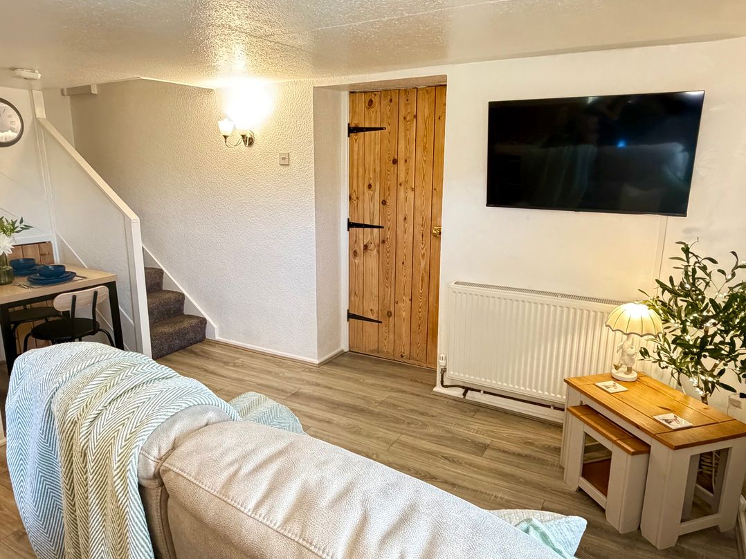 A living room with a staircase and wooden door at Wayside Farm Cart Cottage in Cloughton near Burniston