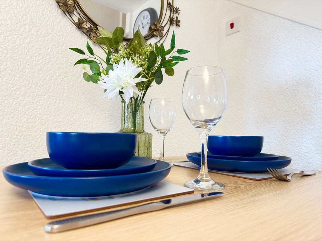 A dining table set with blue plates and glasses at Wayside Farm Cart Cottage in Cloughton near Burniston