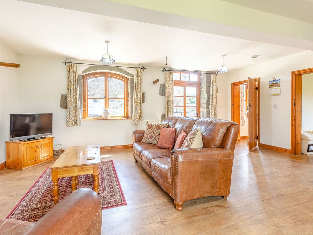 A living room with brown leather sofas a wooden coffee table and a television at Swallow's Nest in Strefford near Craven Arms