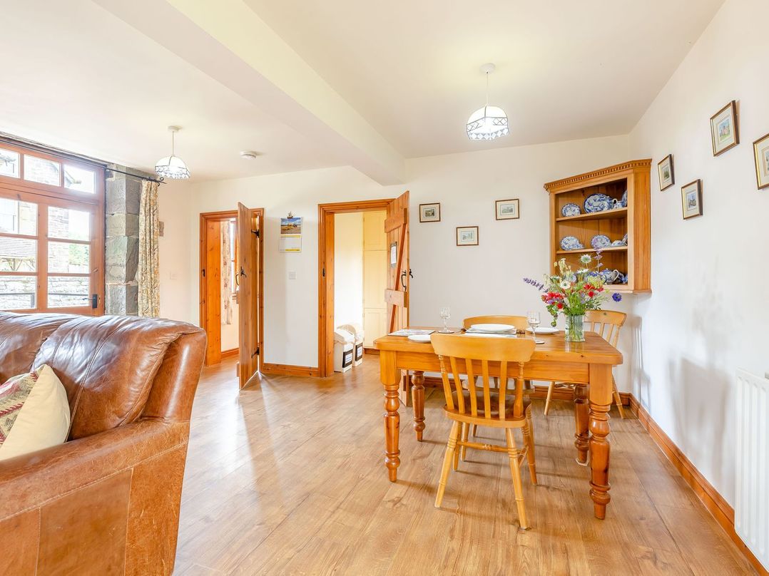 A dining area with wooden dining table and chairs and a leather sofa at Swallow's Nest in Strefford near Craven Arms