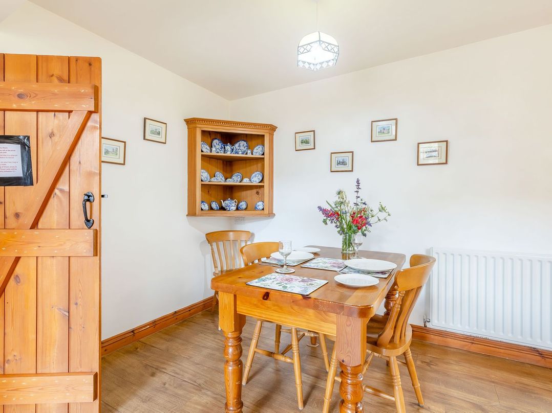 A dining room with wooden furniture and floral place mats at Swallow's Nest in Strefford near Craven Arms