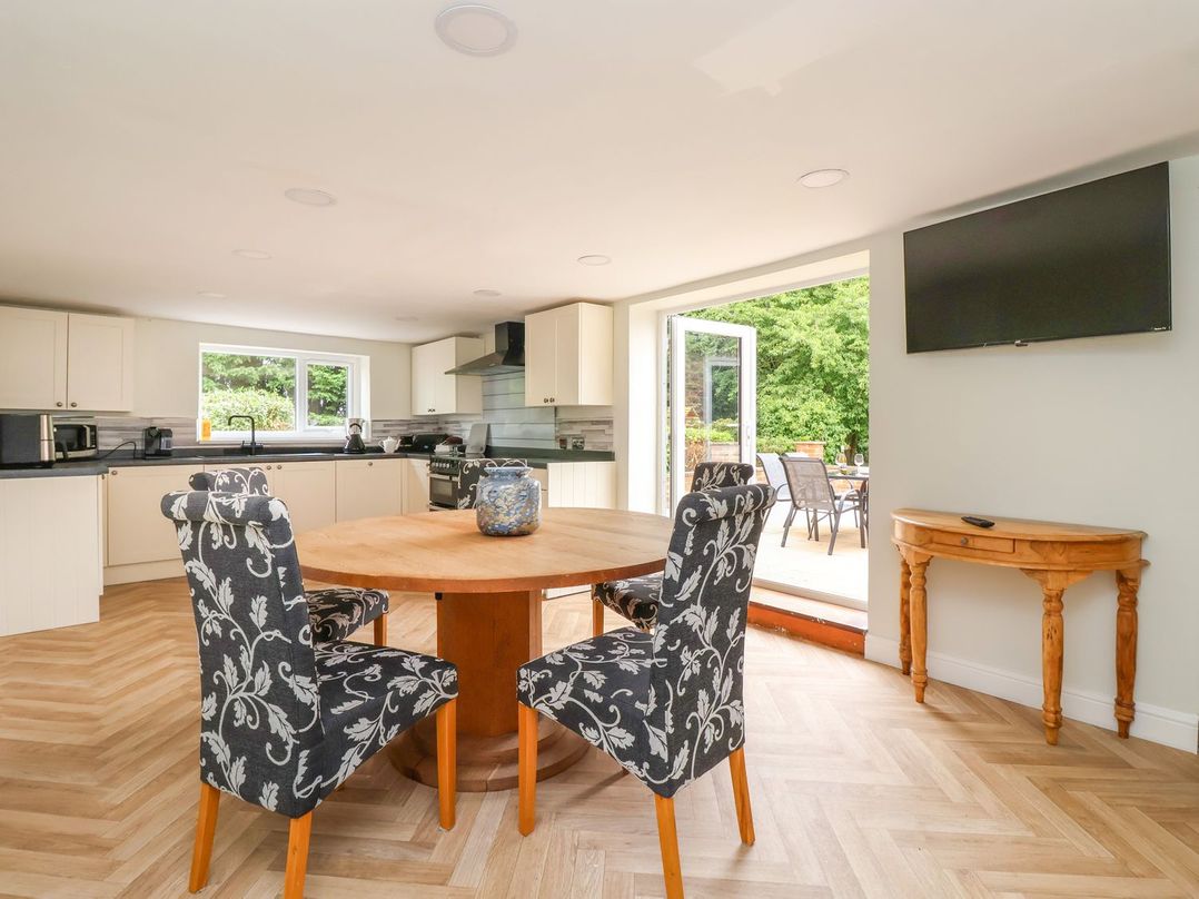 A kitchen and dining area with a round wooden table and four patterned chairs at Bewholme in Skipsea