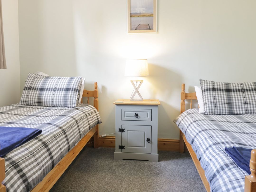 A bedroom with two beds and a nightstand at Cyffdy Cottage - Arenig