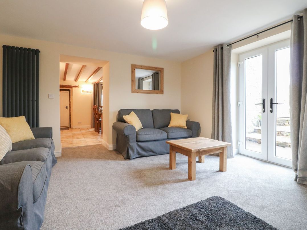 A living room with two grey sofas a wooden coffee table and patio doors at Lane Head Cottage in Alderwasley near Wirksworth