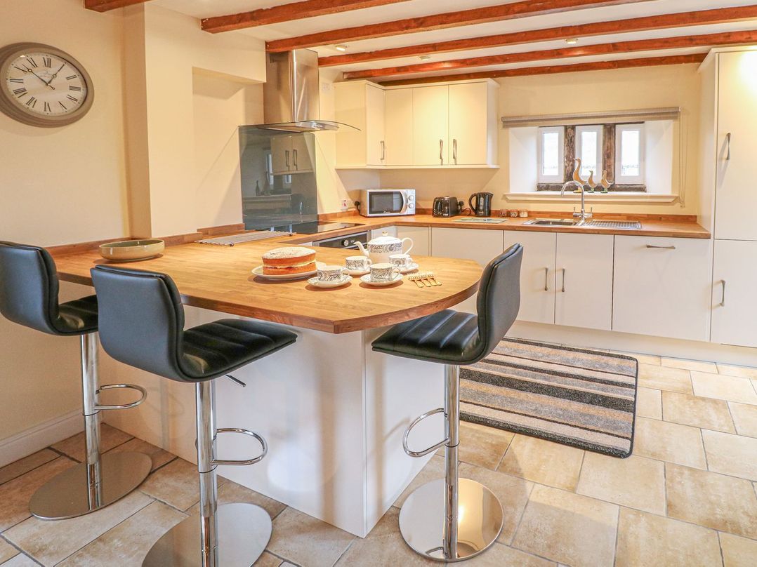 A kitchen with wooden countertops black bar stools and a striped rug at Lane Head Cottage in Alderwasley near Wirksworth