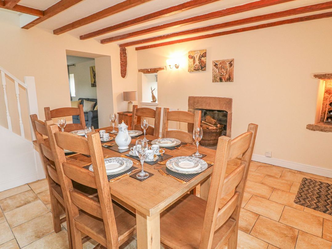 A dining room with a wooden table set for six and a fireplace at Lane Head Cottage in Alderwasley near Wirksworth
