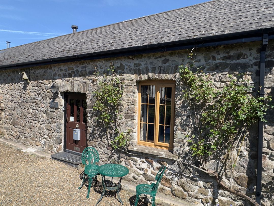 A door and window on a stone wall with a table and chairs at 8 Rogeston Cottages Haverfordwest