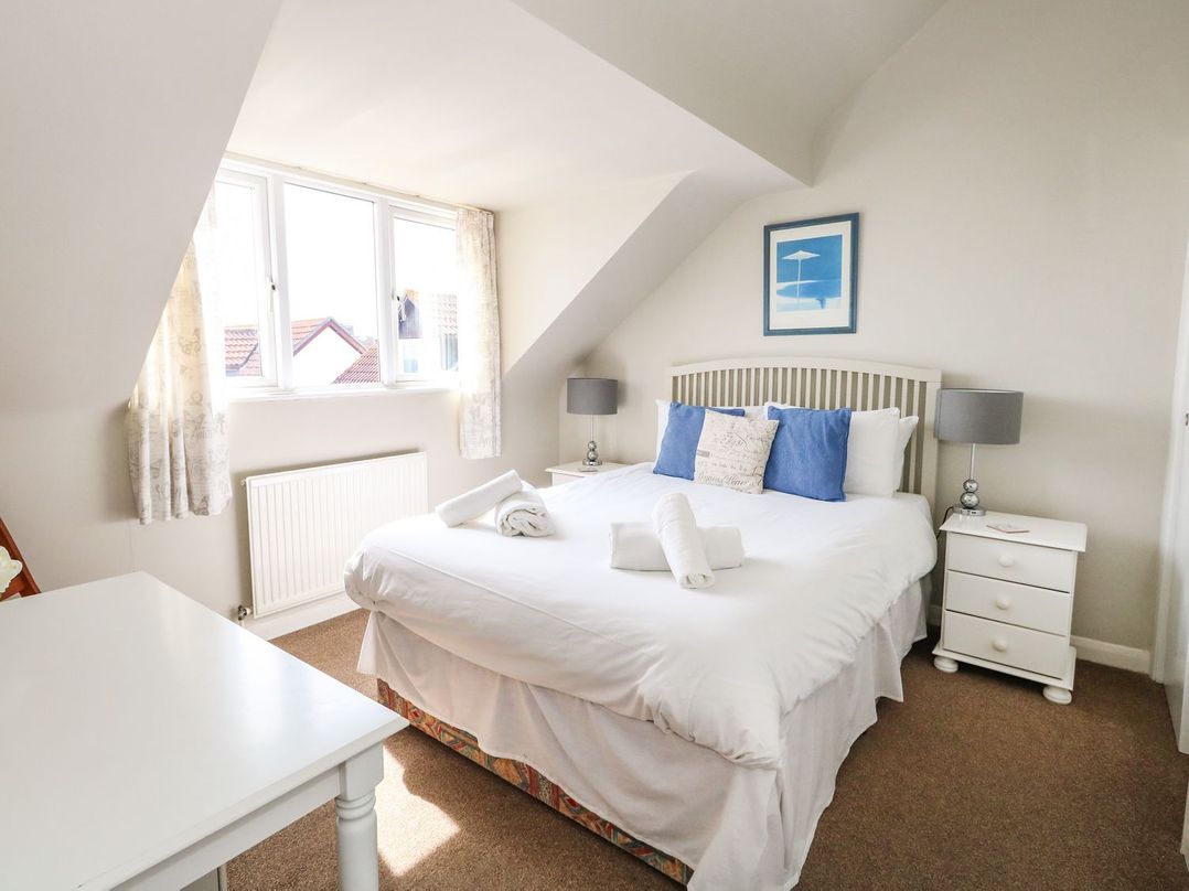 A bedroom with a double bed nightstands lamps and a window at Sea Spray in Bowleaze