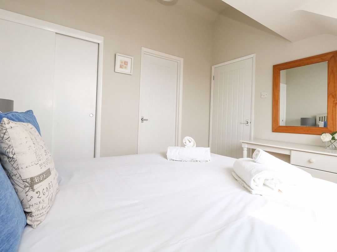 A bedroom with a bed with pillows and towels on it a dresser with a mirror and two doors at Sea Spray in Bowleaze
