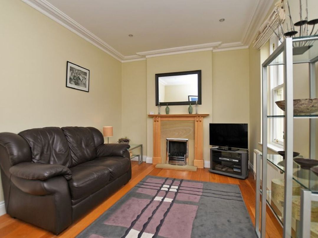 A living room with a leather sofa fireplace and television at Churchside in Alnwick