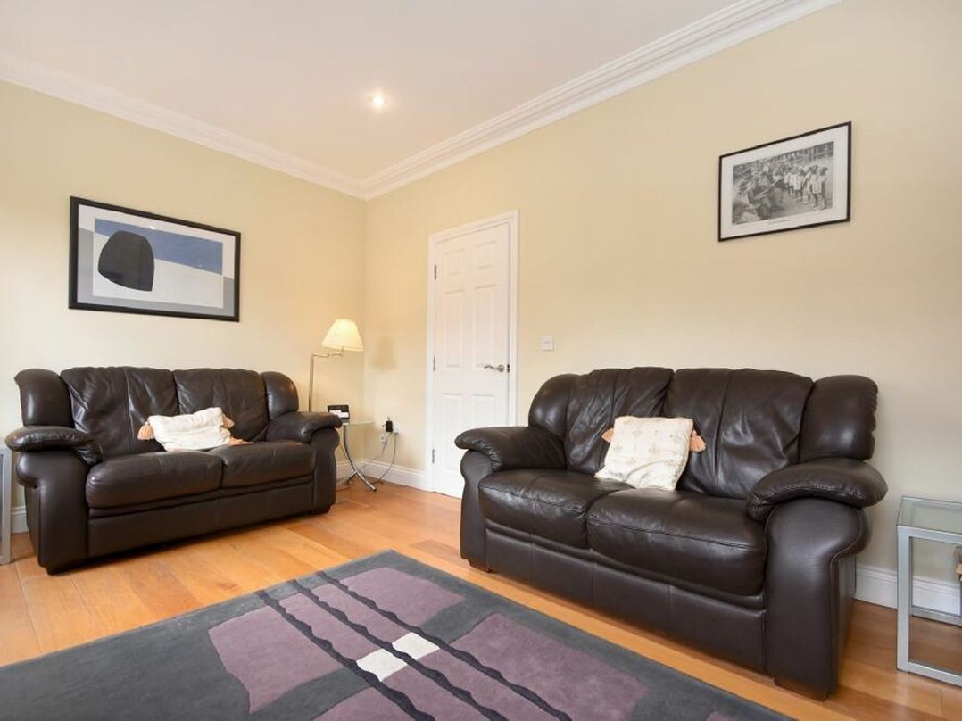 A living room with two brown leather sofas a lamp and framed pictures on the wall at Churchside in Alnwick
